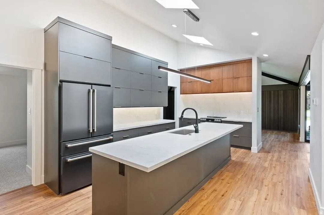 Modern kitchen featuring an expansive center island with an undermount sink and matte black faucet