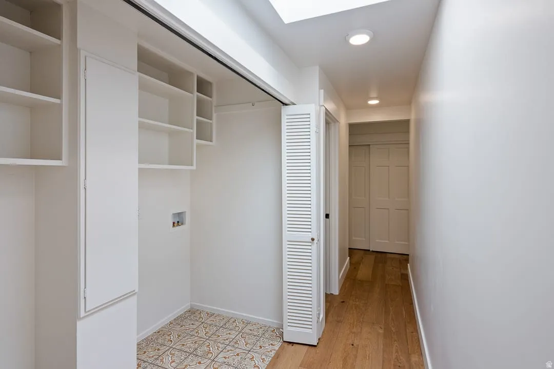 Laundry area featuring patterned floor tile, built-in shelving, and a skylight