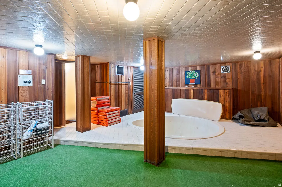 Recreational room featuring a built-in spa, wood paneling, and a tiled platform