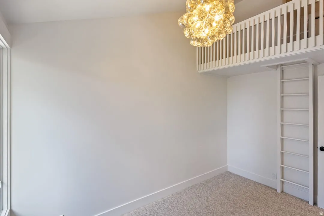 Loft space featuring a decorative light fixture, built-in ladder, and light-colored carpeting