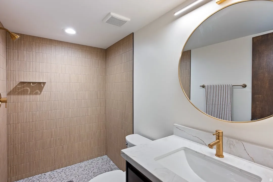 Bathroom featuring a walk-in shower with textured tile walls, a built-in shower niche, and pebbled flooring
