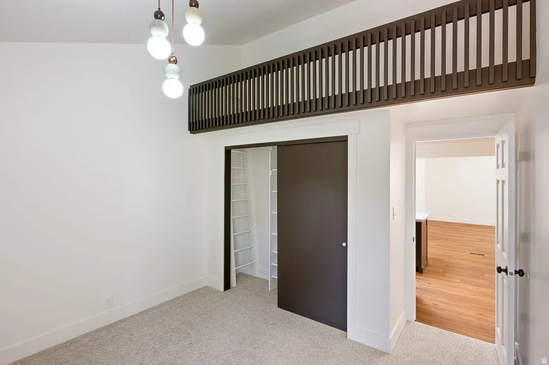 Carpeted room featuring a built-in loft structure with slat railing