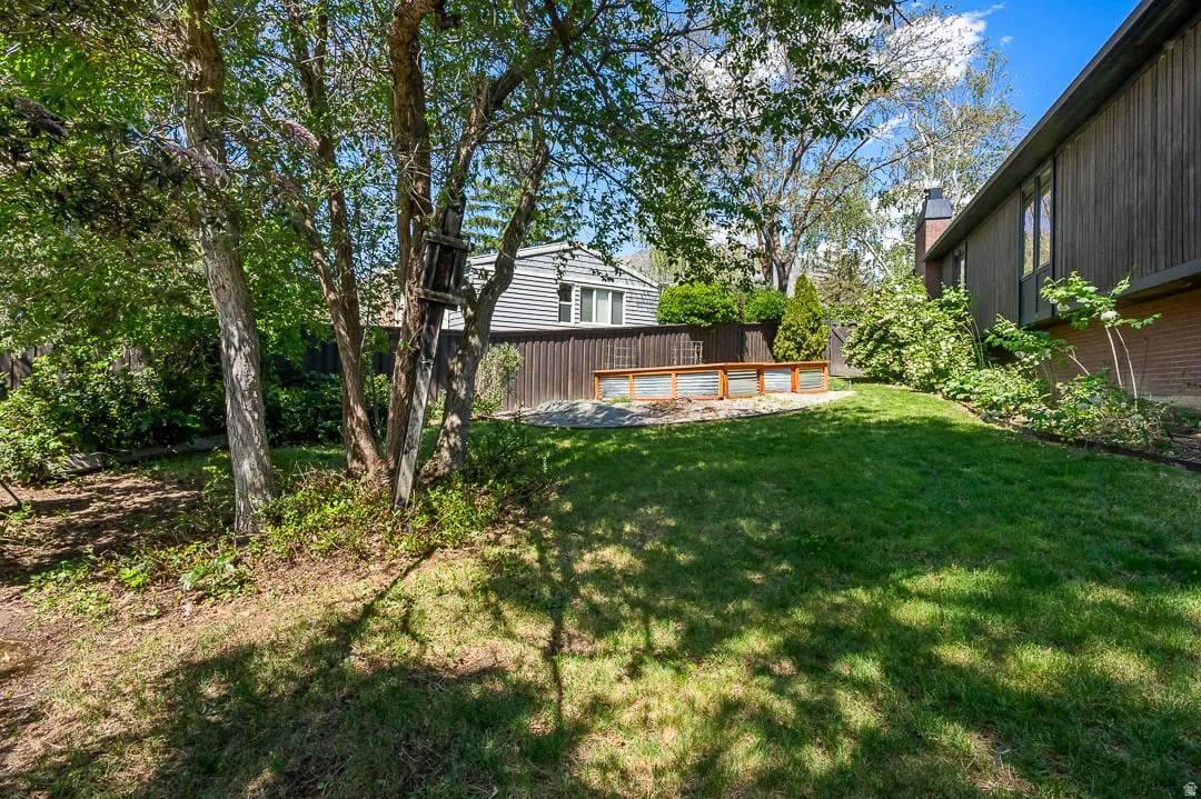 Expansive backyard featuring a manicured lawn, established trees, and a built-in raised garden bed