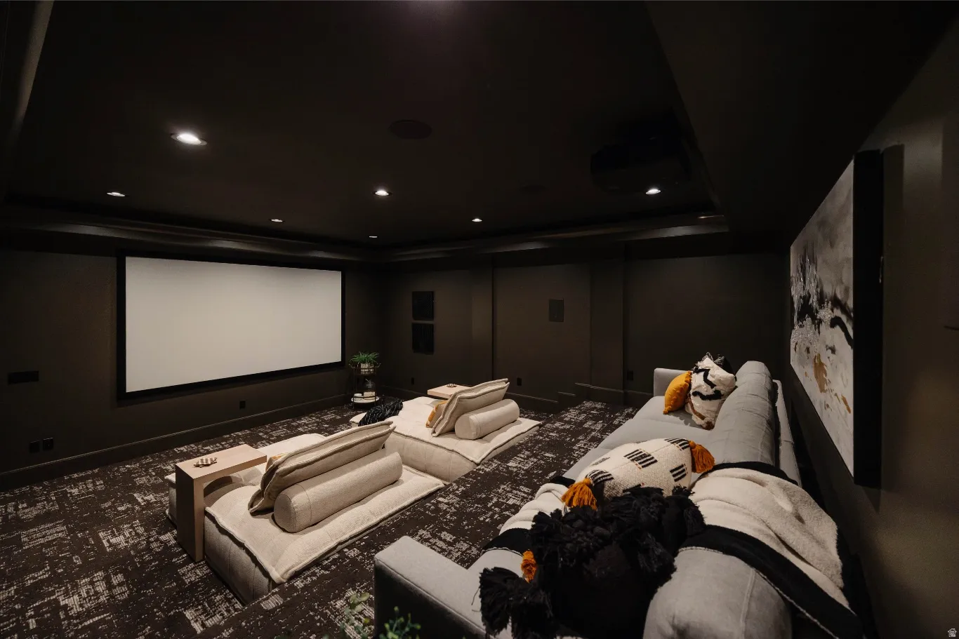 Dedicated media room featuring a large projection screen, recessed ceiling lighting, and dark walls for optimal viewing