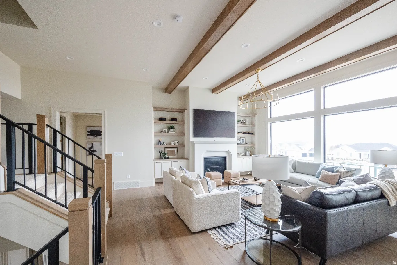 Spacious living area featuring expansive windows, wood-finish flooring, and exposed ceiling beams