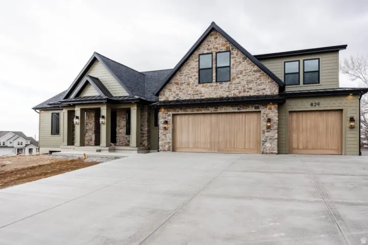Contemporary residence featuring a stone and siding exterior, multiple gables, and a prominent front entry with columns