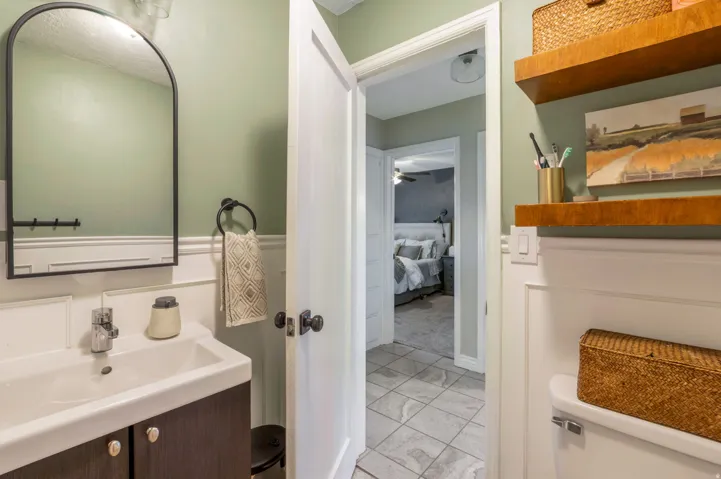 Bathroom featuring a white vanity with dark wood-finish cabinetry, a rectangular sink, and a black-framed arched mirror
