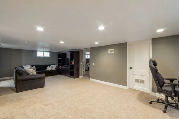 Spacious carpeted room featuring recessed lighting, painted walls, white baseboards, and a white interior door with a paneled design