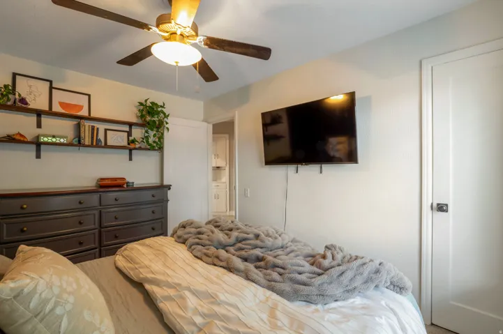 Interior room featuring a ceiling fan with integrated lighting, wall-mounted shelving, white interior doors, and neutral wall tones