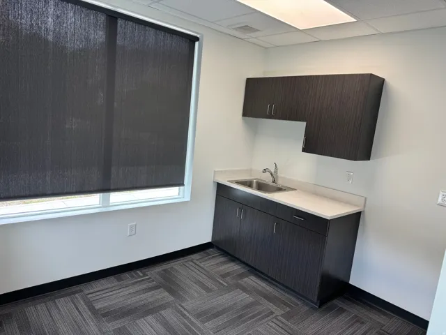 Utility sink with stainless steel faucet, light-toned countertop, and dark wood-finish cabinetry