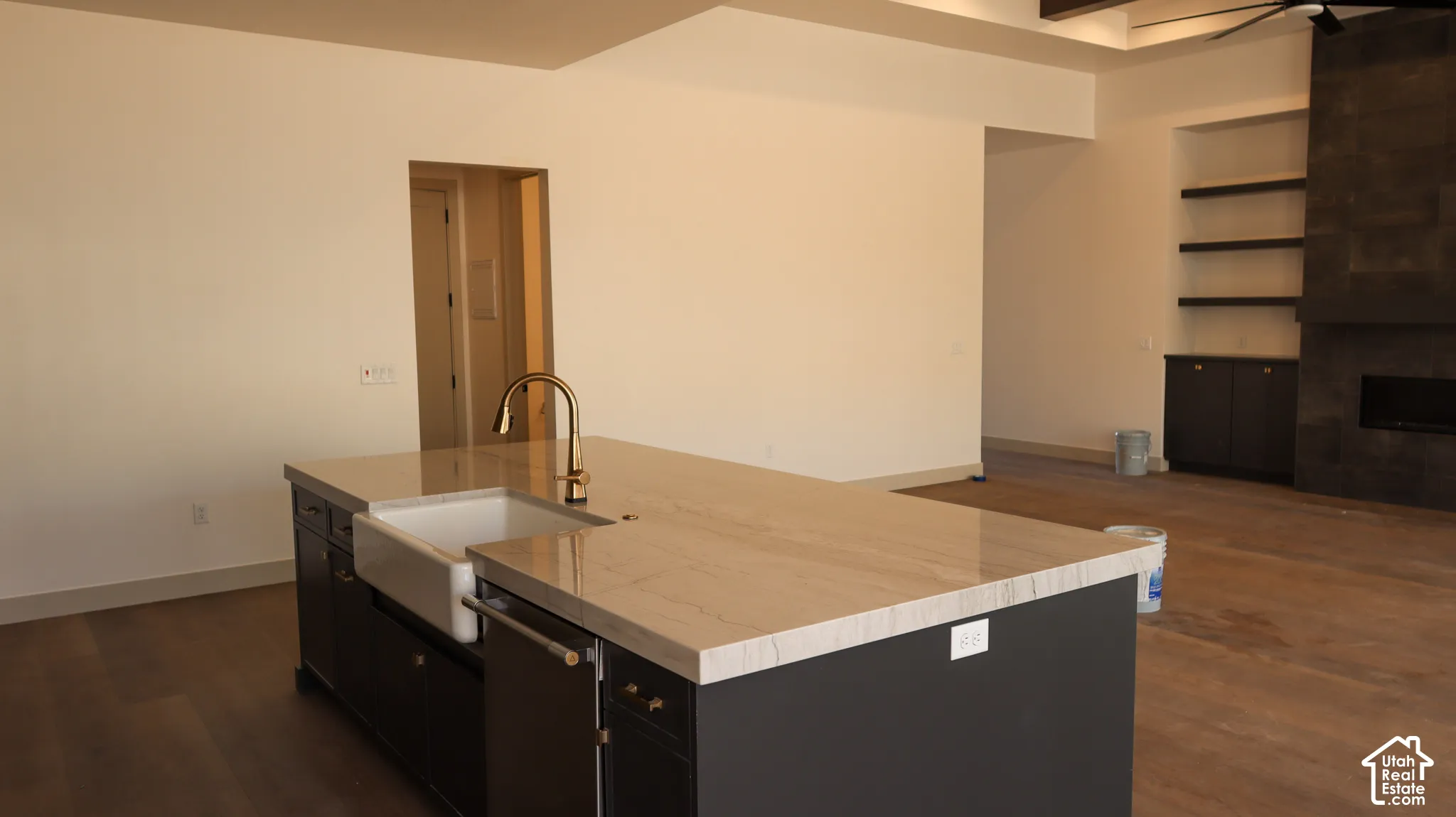 Kitchen island featuring a farmhouse sink, gold-tone faucet, and light-toned countertop