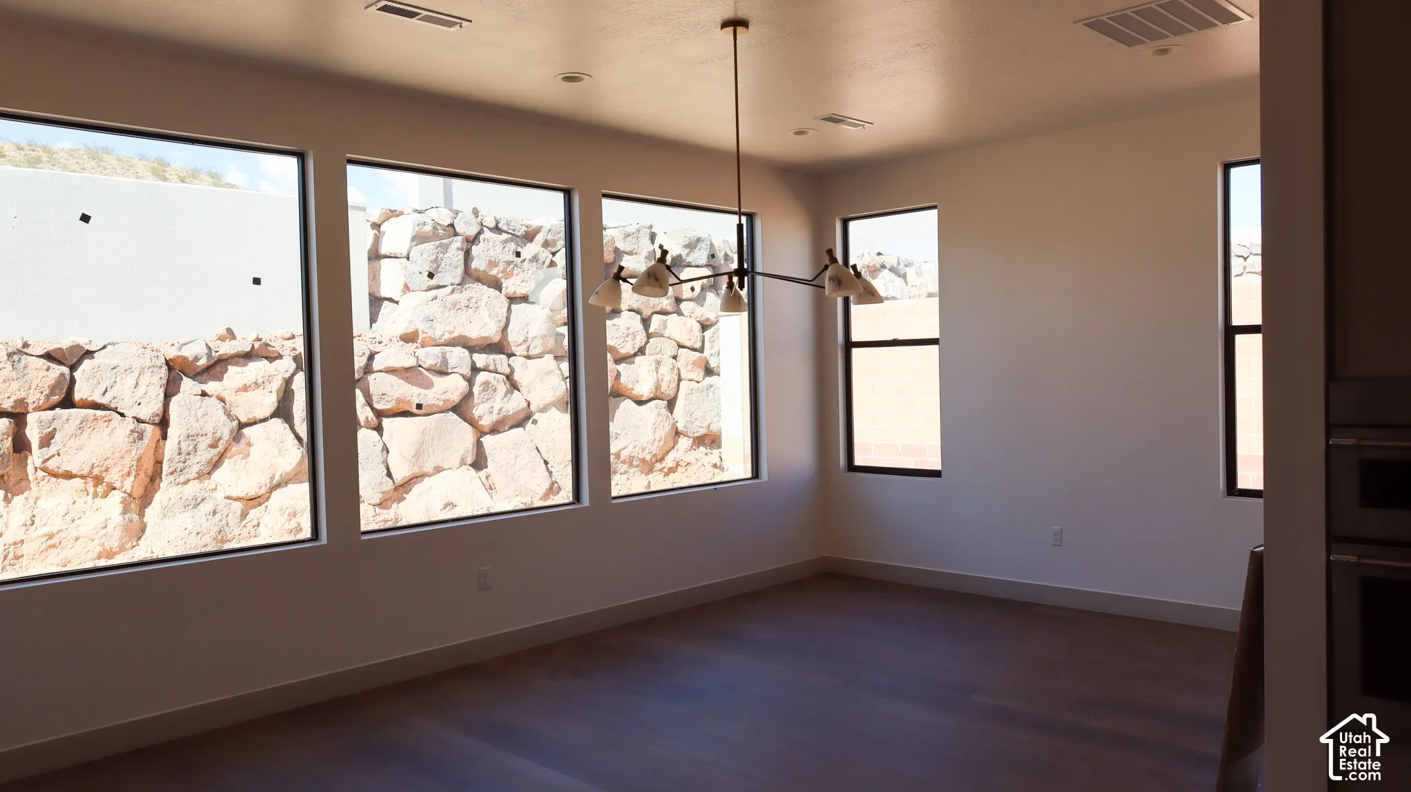 Expansive windows with black trim, contemporary chandelier, recessed lighting, and wood-finish flooring