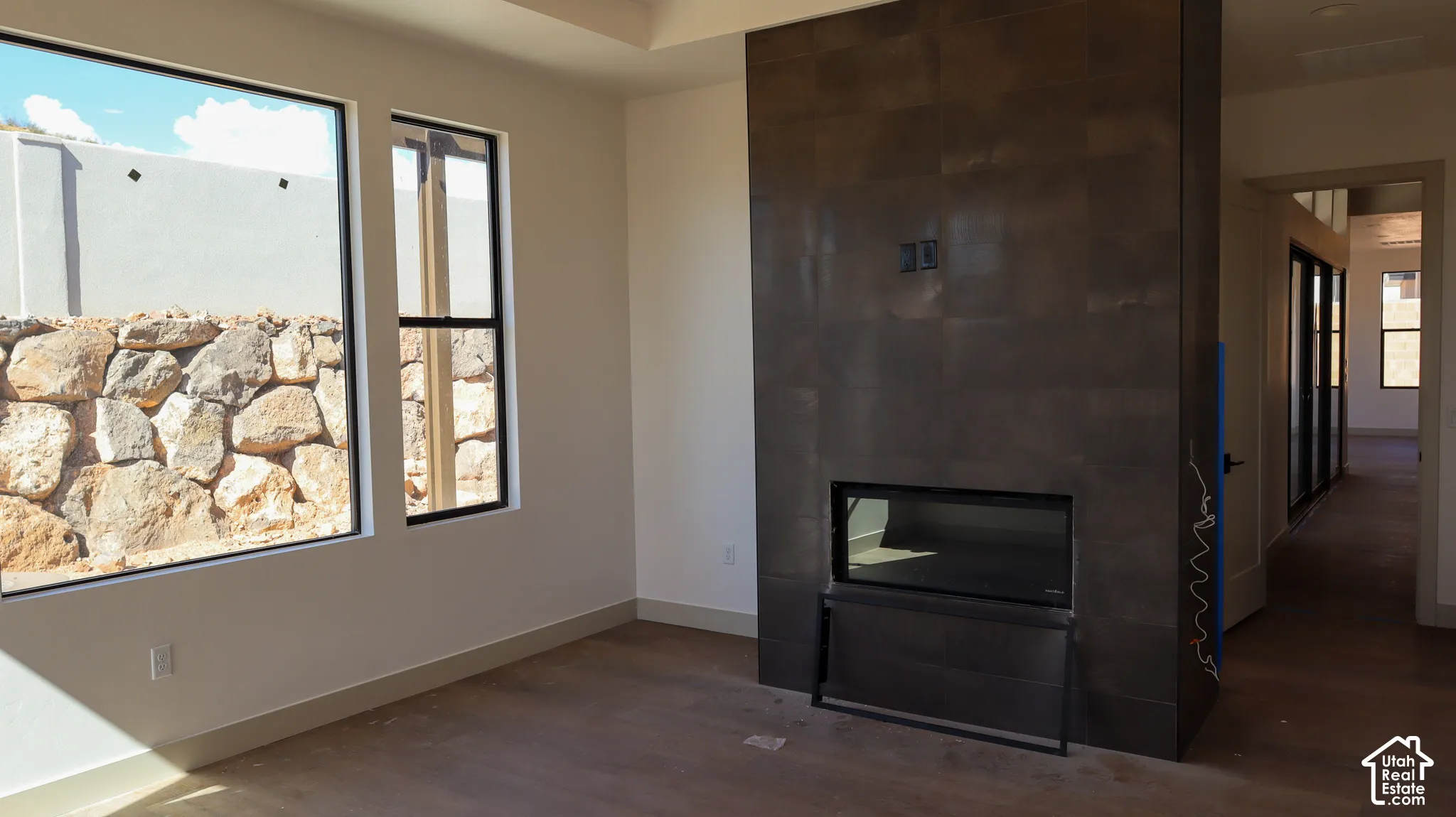 Integrated fireplace with a dark-toned surround, wood-finish flooring, and large windows