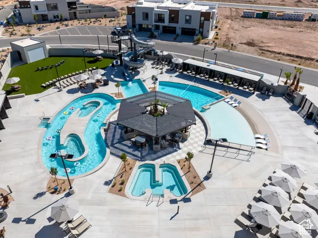 Outdoor aquatic area featuring multiple pools, a lazy river, water slide, and shaded lounge seating