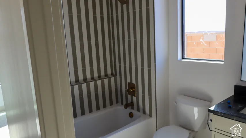 Bathtub with vertically striped tile surround, built-in shower niche, and bronze fixtures