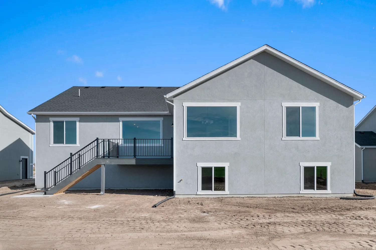 Rear elevation featuring a gray stucco finish and multiple windows