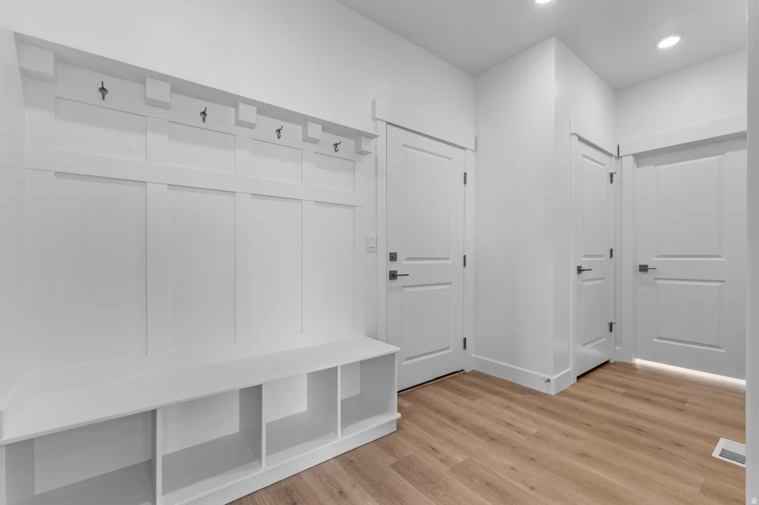 Built-in white board and batten mudroom bench featuring cubby storage and five coat hooks