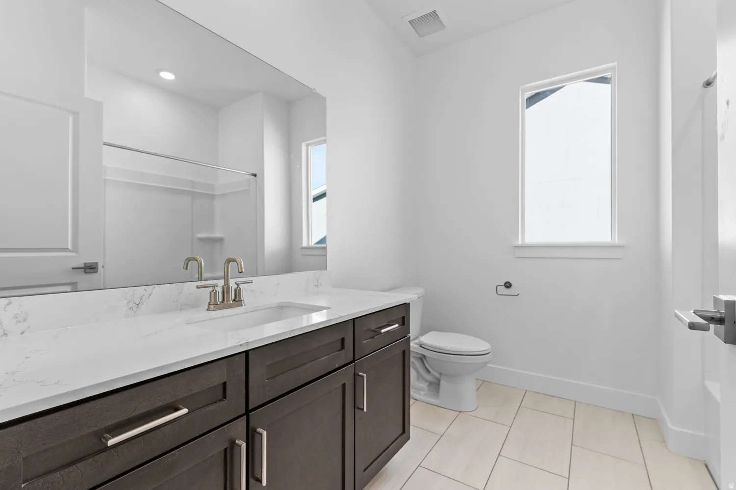 Bathroom featuring a dark wood-finish vanity with a light countertop, a rectangular undermount sink, and a brushed nickel faucet