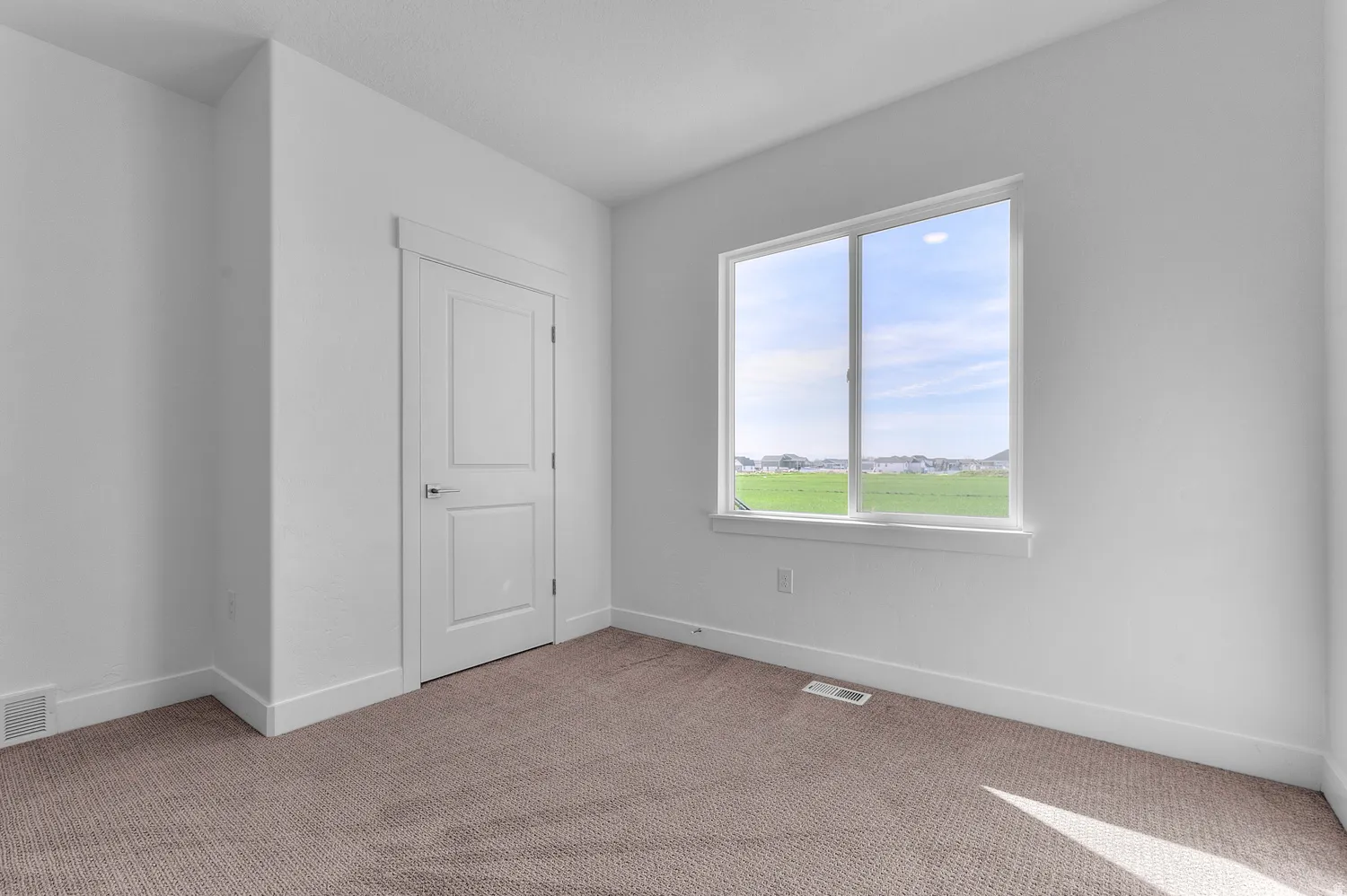 Neutral color palette room featuring a large window, white trim, and light brown carpeting
