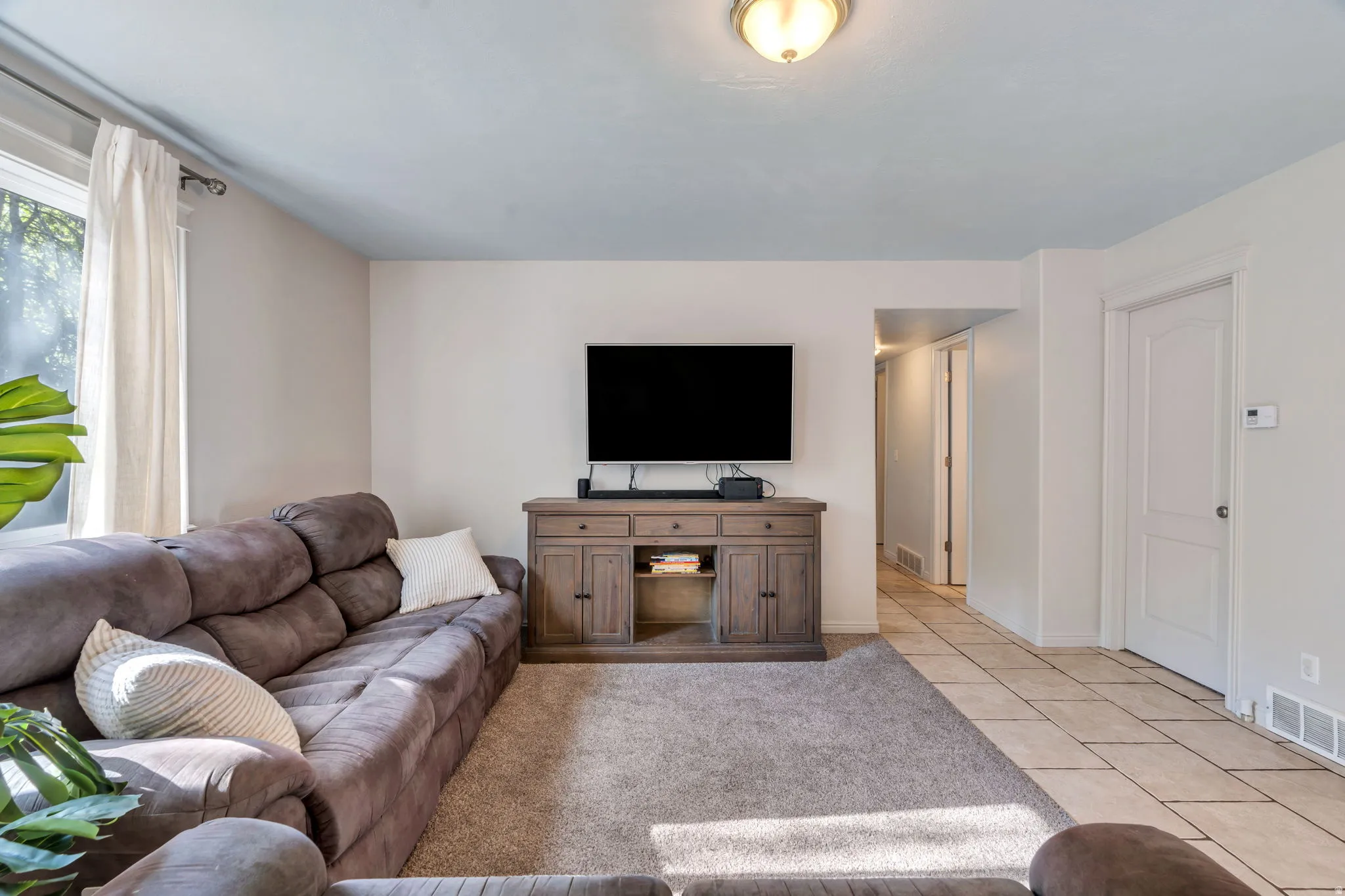 Open concept living area featuring a large window with natural light, light gray wall paint, and a built-in entertainment console