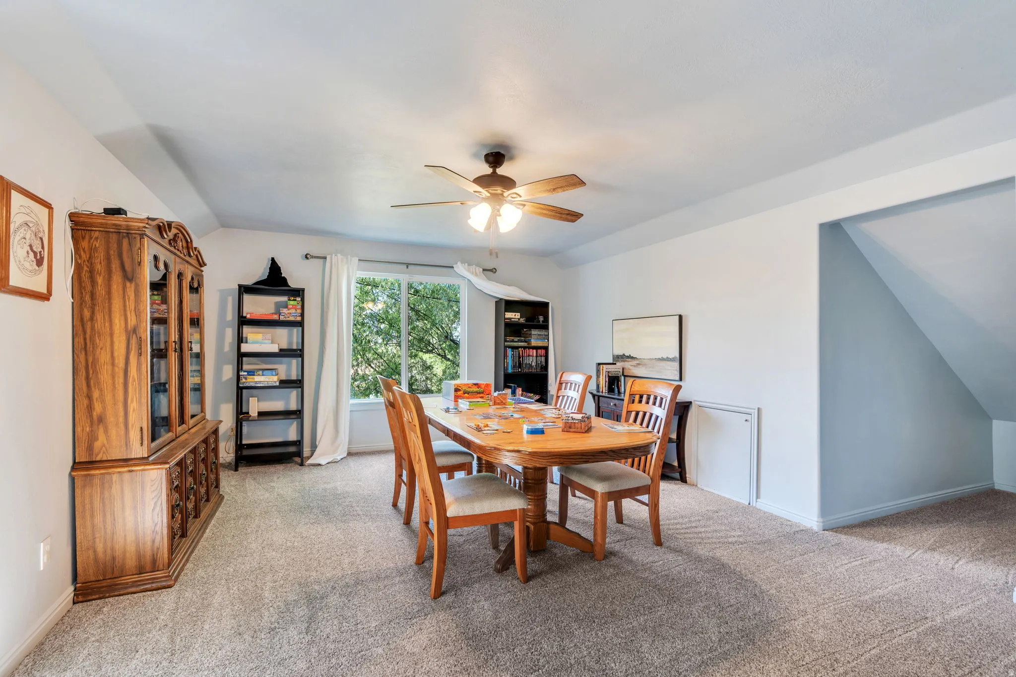 Spacious room with sloped ceilings and light-colored carpeting