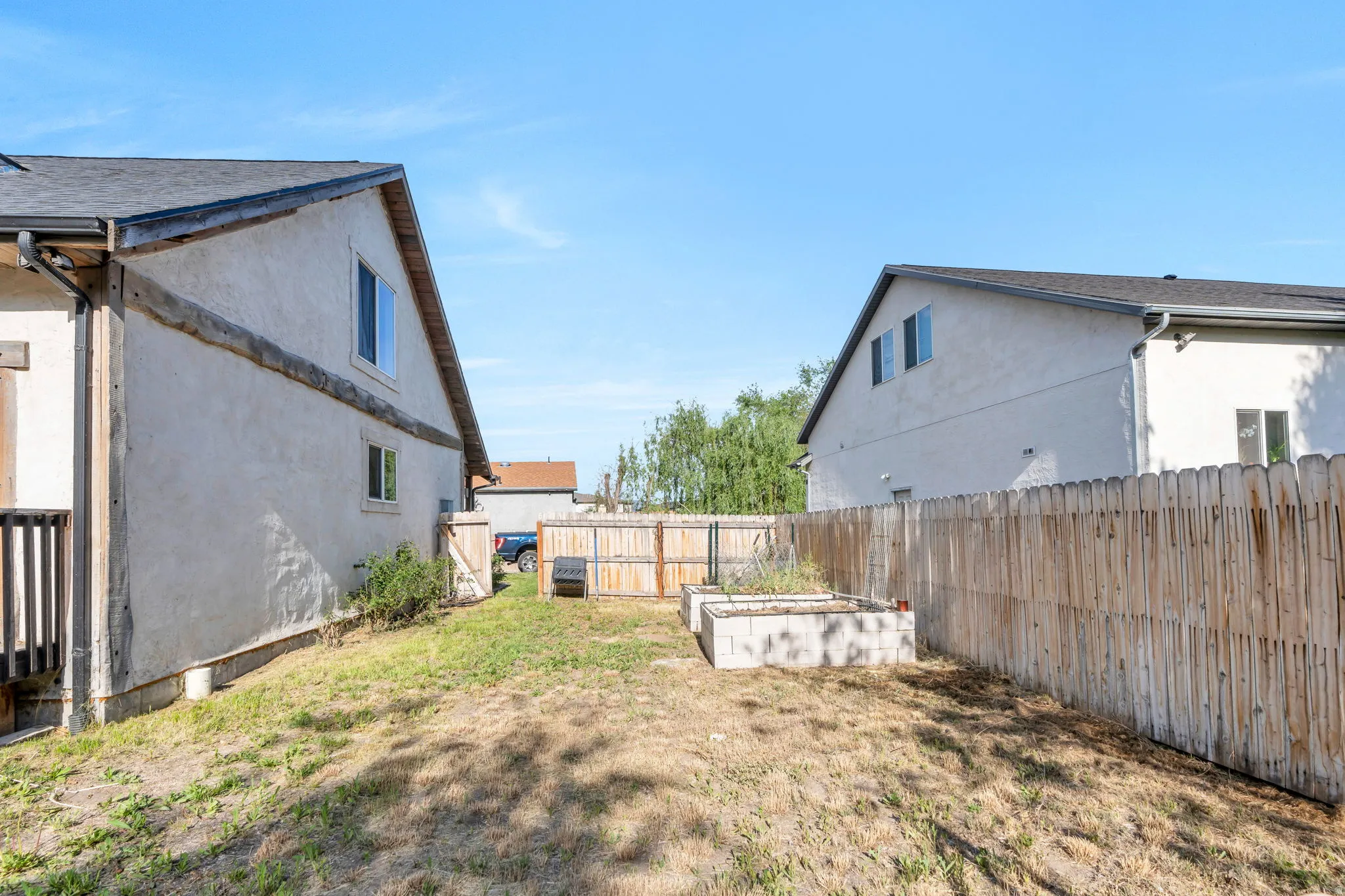 Expansive backyard featuring a wood fence, concrete raised garden beds, and a multi-level deck with wood railings