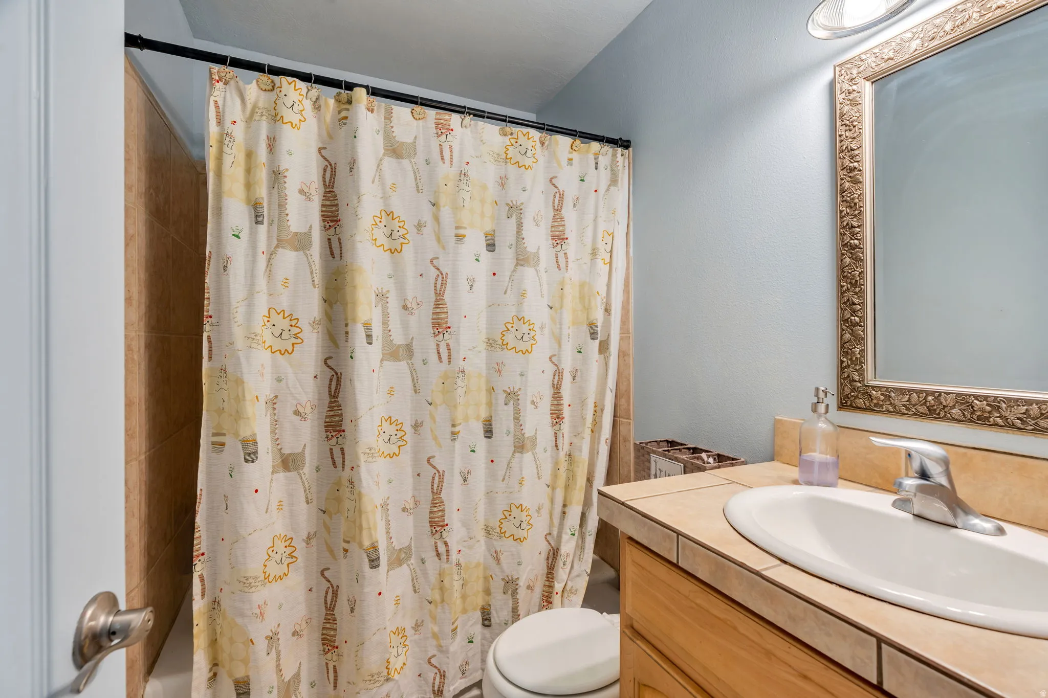 Bathroom vanity featuring a tiled countertop, undermount sink, and wood-finish cabinetry