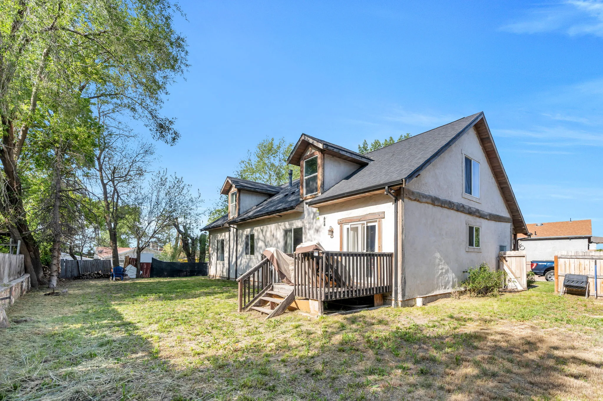 Rear exterior featuring an elevated wood deck, stucco siding, and a gabled roofline