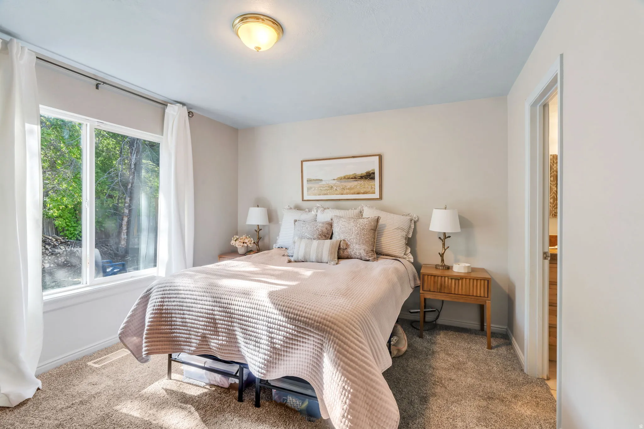Bedroom featuring neutral-toned walls, plush carpeting, and a window with white trim