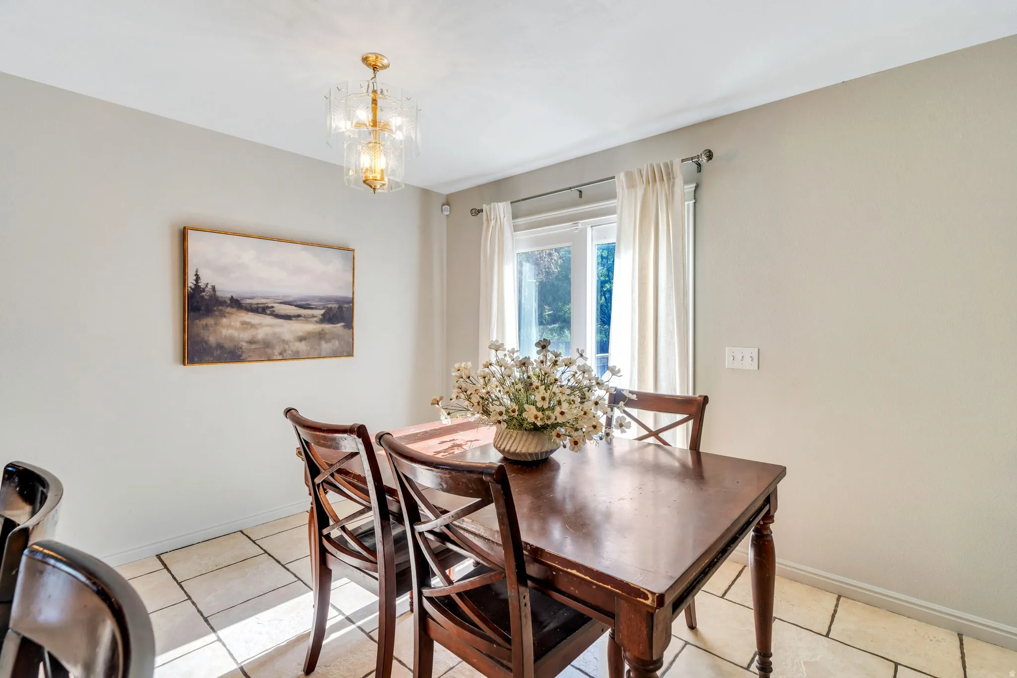 Dining area featuring light-toned tile flooring, a window with natural light, and a decorative ceiling light fixture