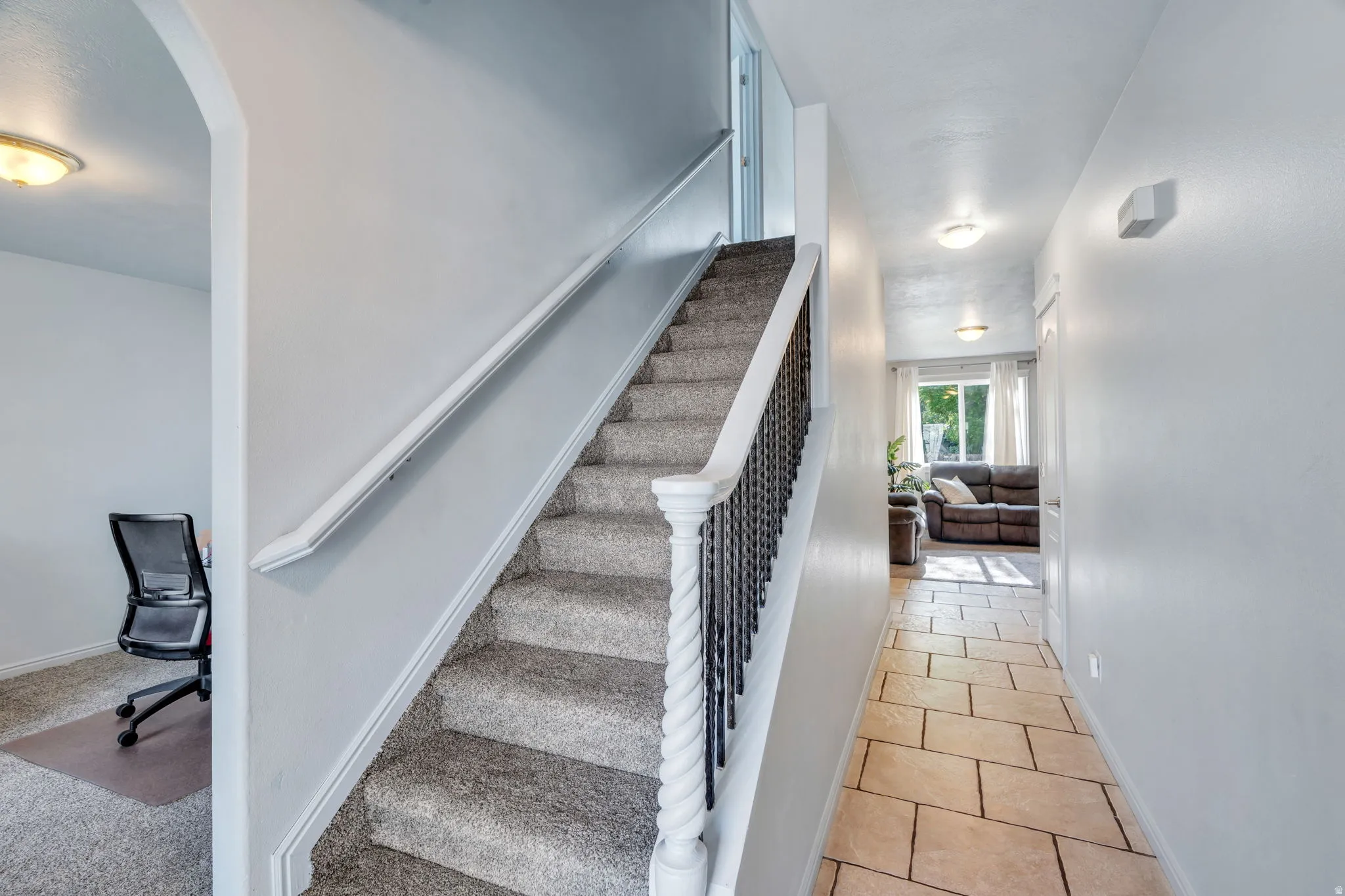 Carpeted staircase with white newel posts and black metal balusters