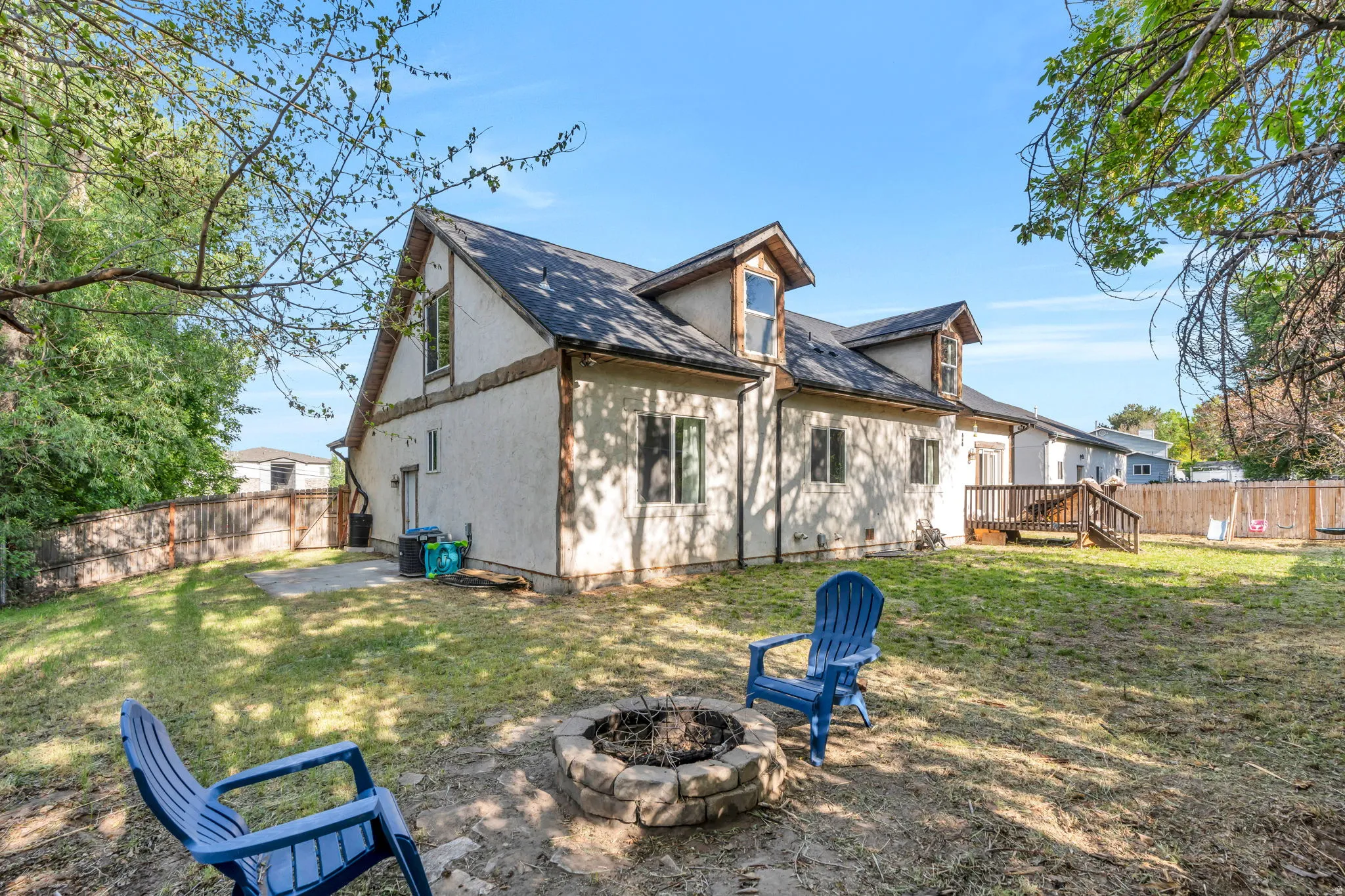 Spacious backyard with a stone fire pit, wood privacy fencing, and a raised wood deck