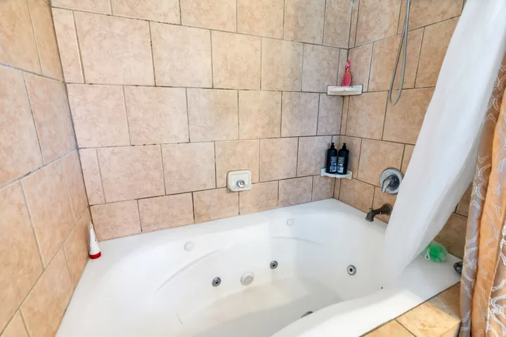 Tiled shower and tub surround featuring a built-in jetted tub
