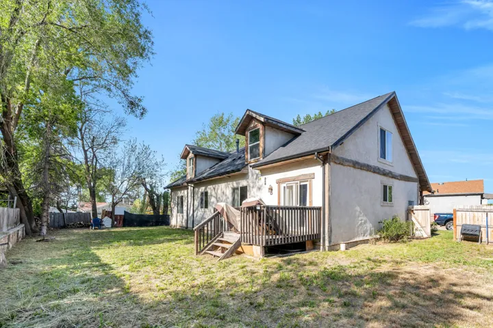 Rear exterior featuring an elevated wood deck, stucco siding, and a gabled roofline