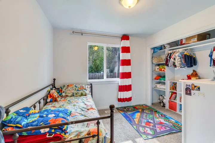 Carpeted room featuring a window with white trim, a built-in closet with shelving and hanging rods, and a flush-mount ceiling light fixture