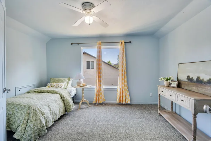 Carpeted room featuring a ceiling fan with integrated lighting, a window with a curtain rod, and light blue wall tones