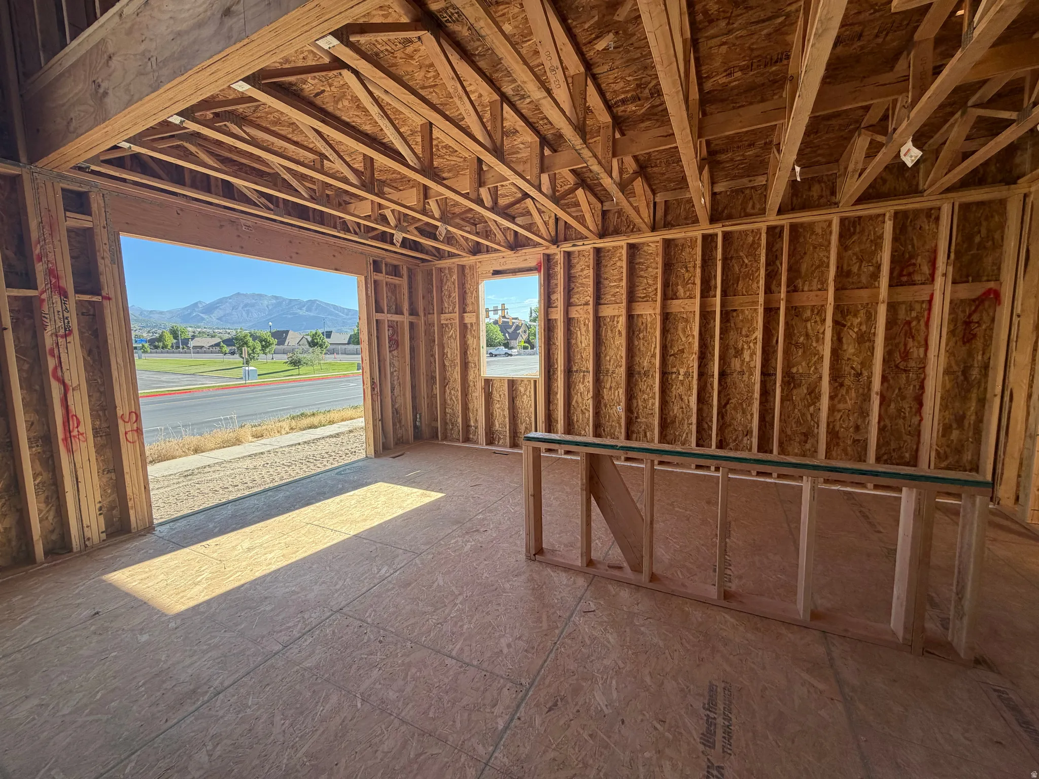 New construction framing with an open garage door framing a mountain backdrop