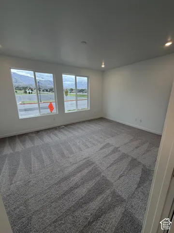 Owner's suite with neutral-toned carpeting, recessed lighting, and large windows with mountain scenery