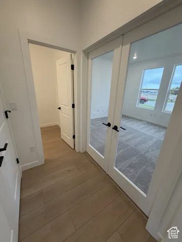 French-style doors with glass paneling, wood-finish flooring, and crisp white interior trim