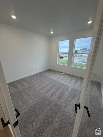 Room featuring neutral carpeting, recessed ceiling lighting, and two large vertical windows with matte black door hardware
