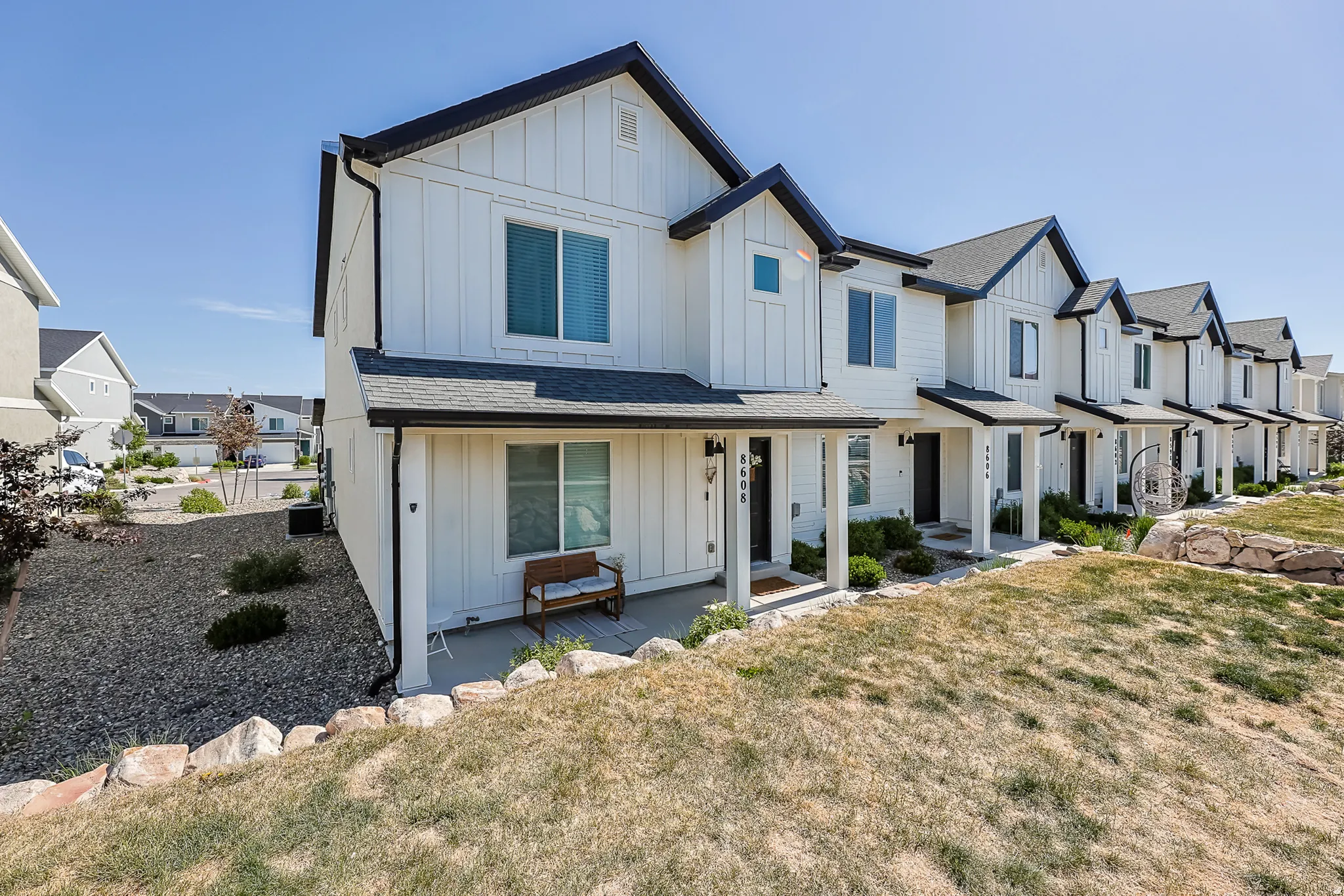 Modern farmhouse-style townhome featuring white board and batten siding, dark trim accents, and a covered front porch
