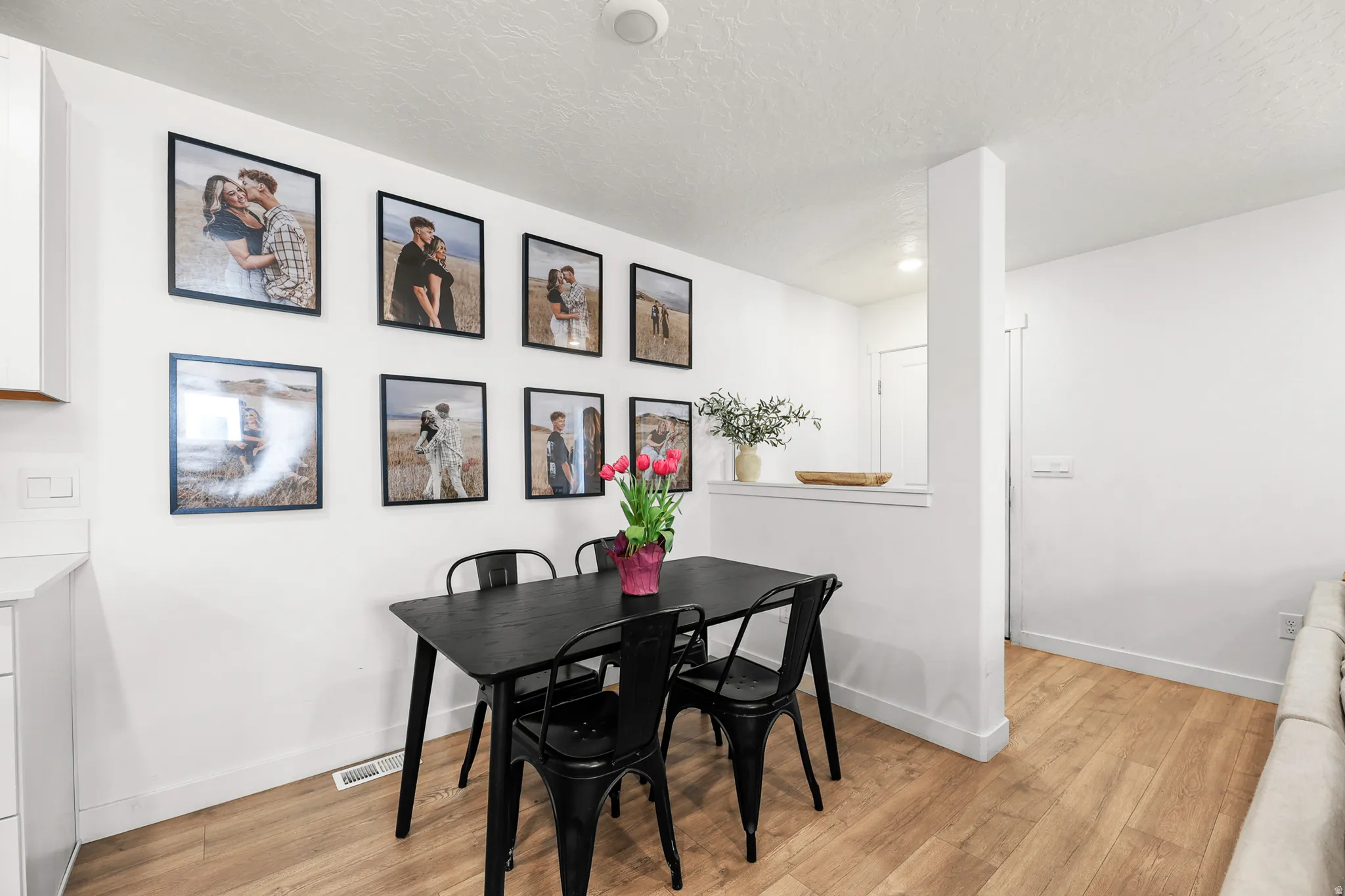 Dining area featuring light wood-finish flooring, white walls, and a partial wall separating spaces