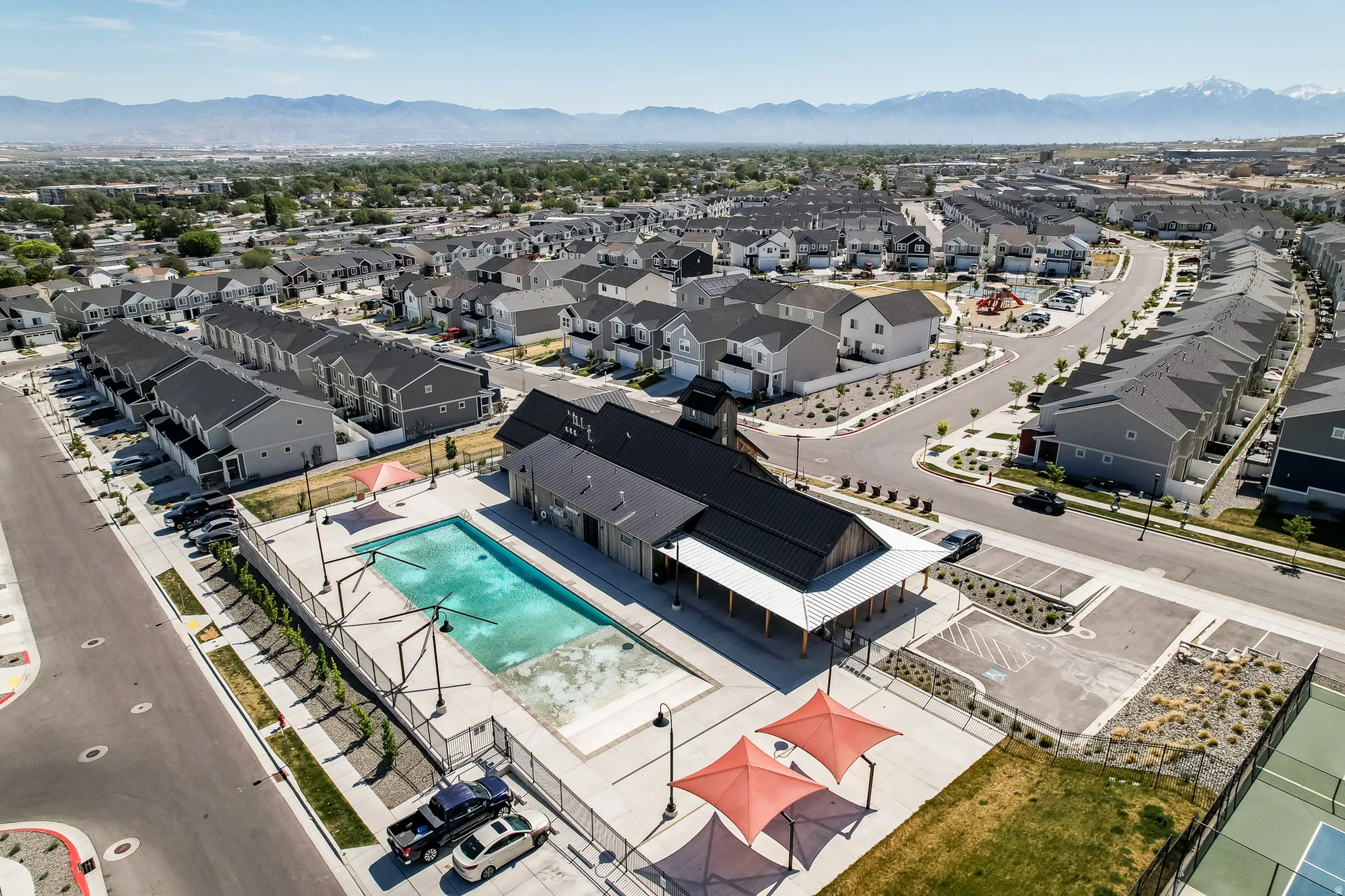 Community recreation area featuring an outdoor swimming pool, tennis courts, and a modern clubhouse