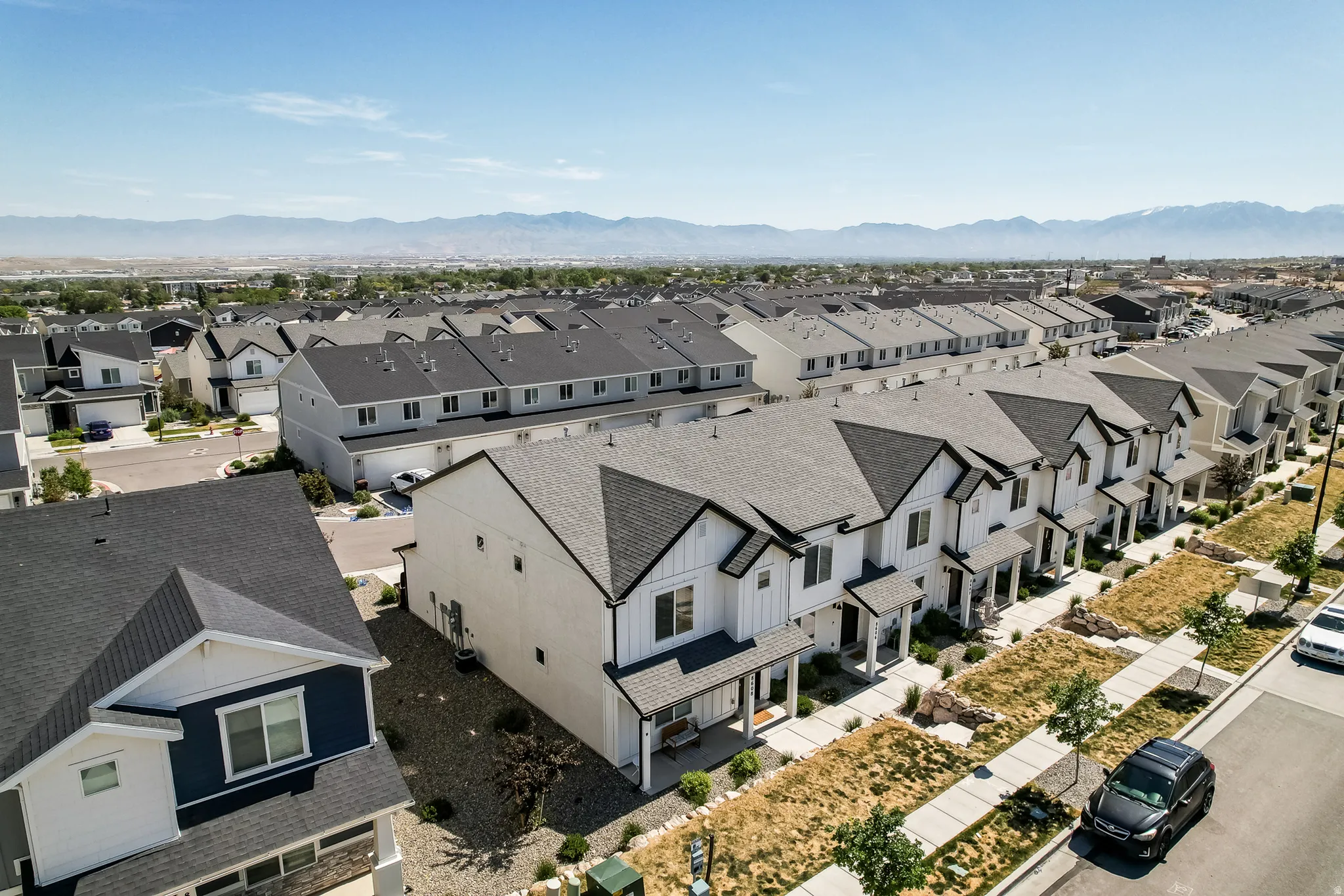 Streetscape featuring contemporary townhomes with dark shingled roofs and white facades