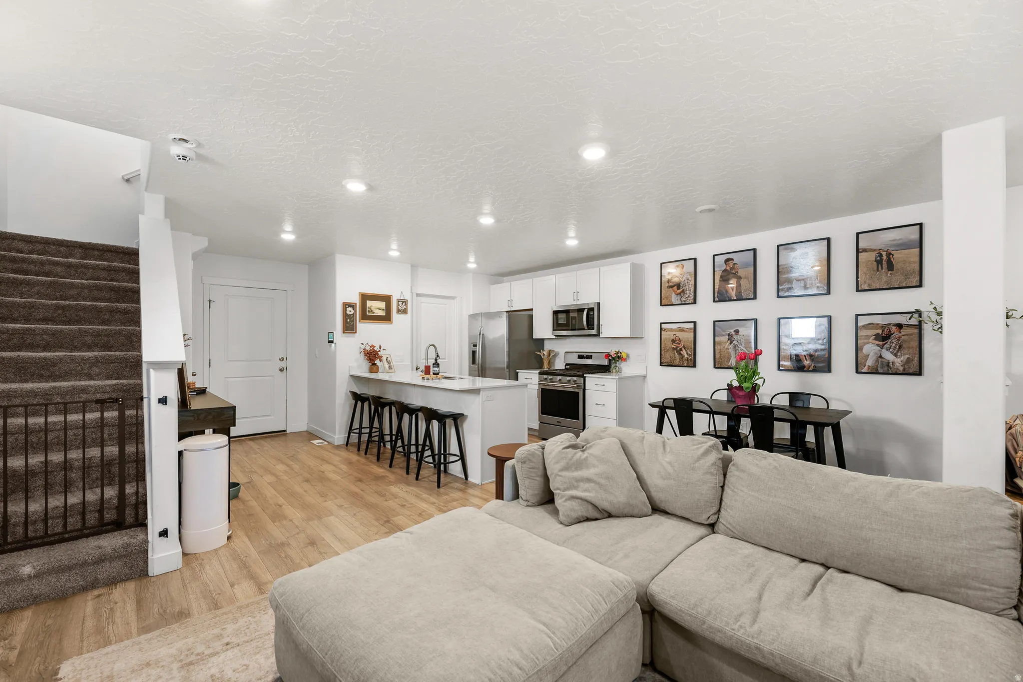 Open-concept living area featuring wood-finish flooring, recessed lighting, and a neutral color palette