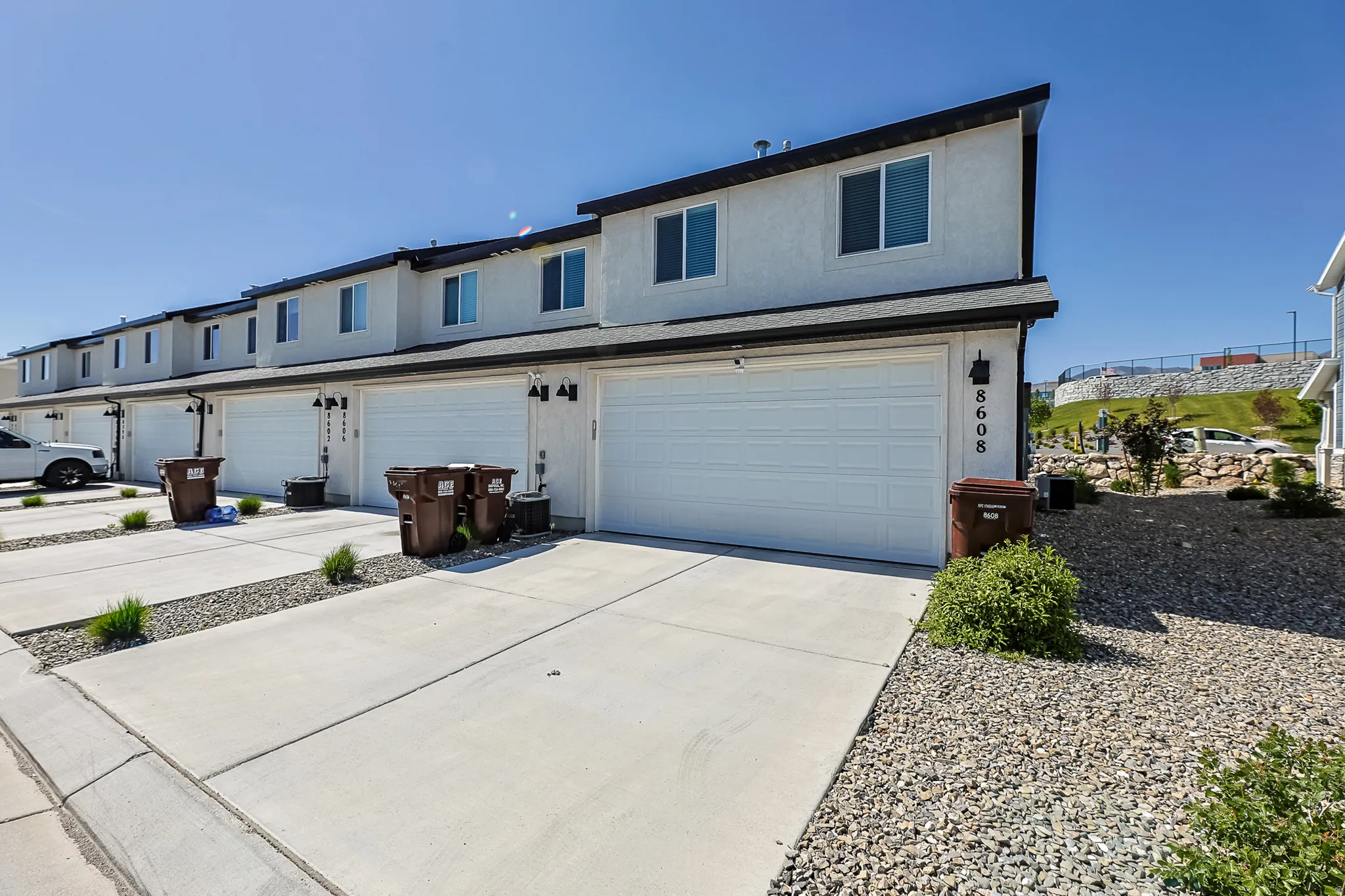 Contemporary townhome exterior featuring an attached two-car garage, white stucco facade, and black trim accents
