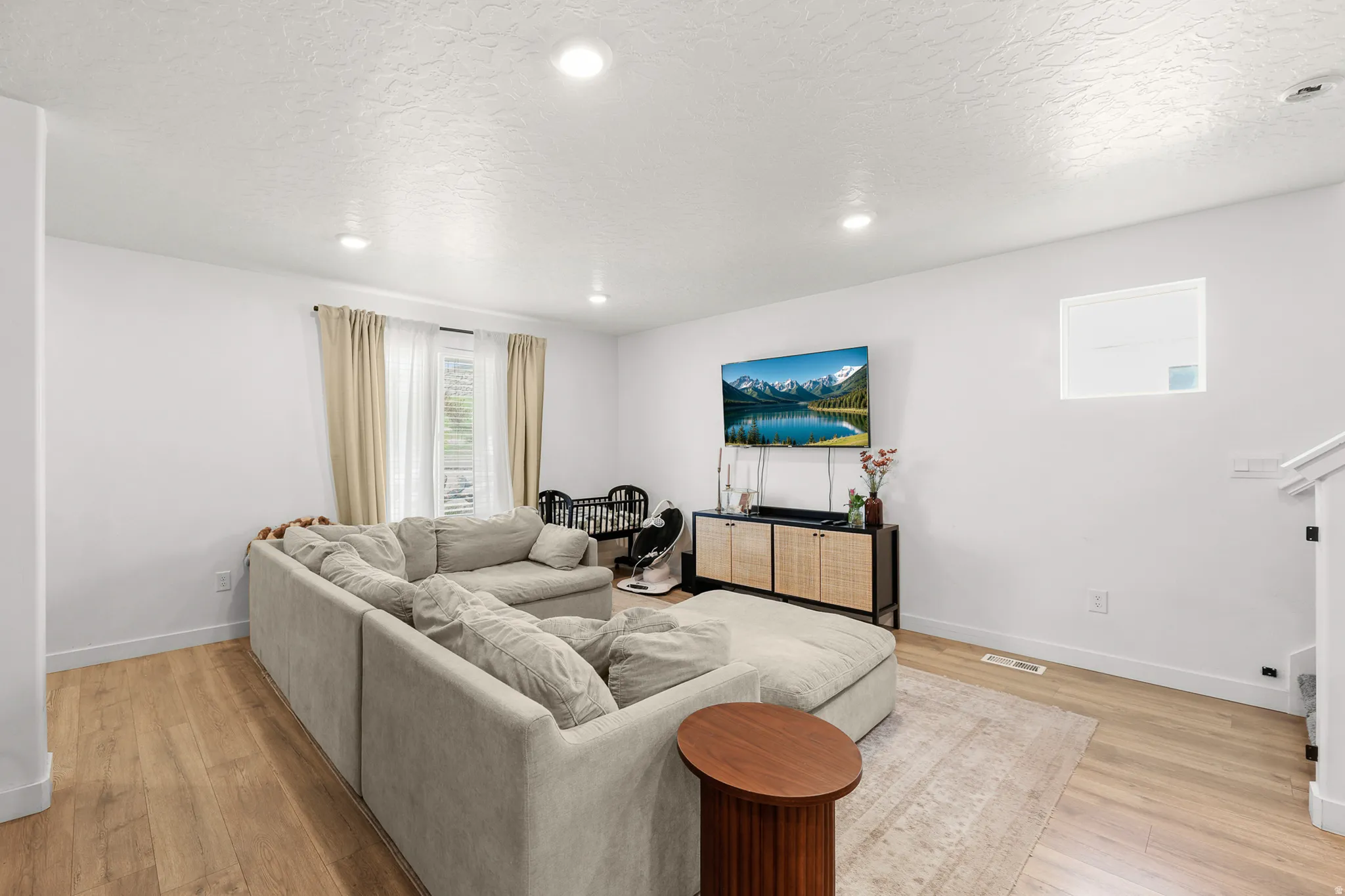 Open-concept living space featuring wood-finish flooring, recessed lighting, and white wall finishes