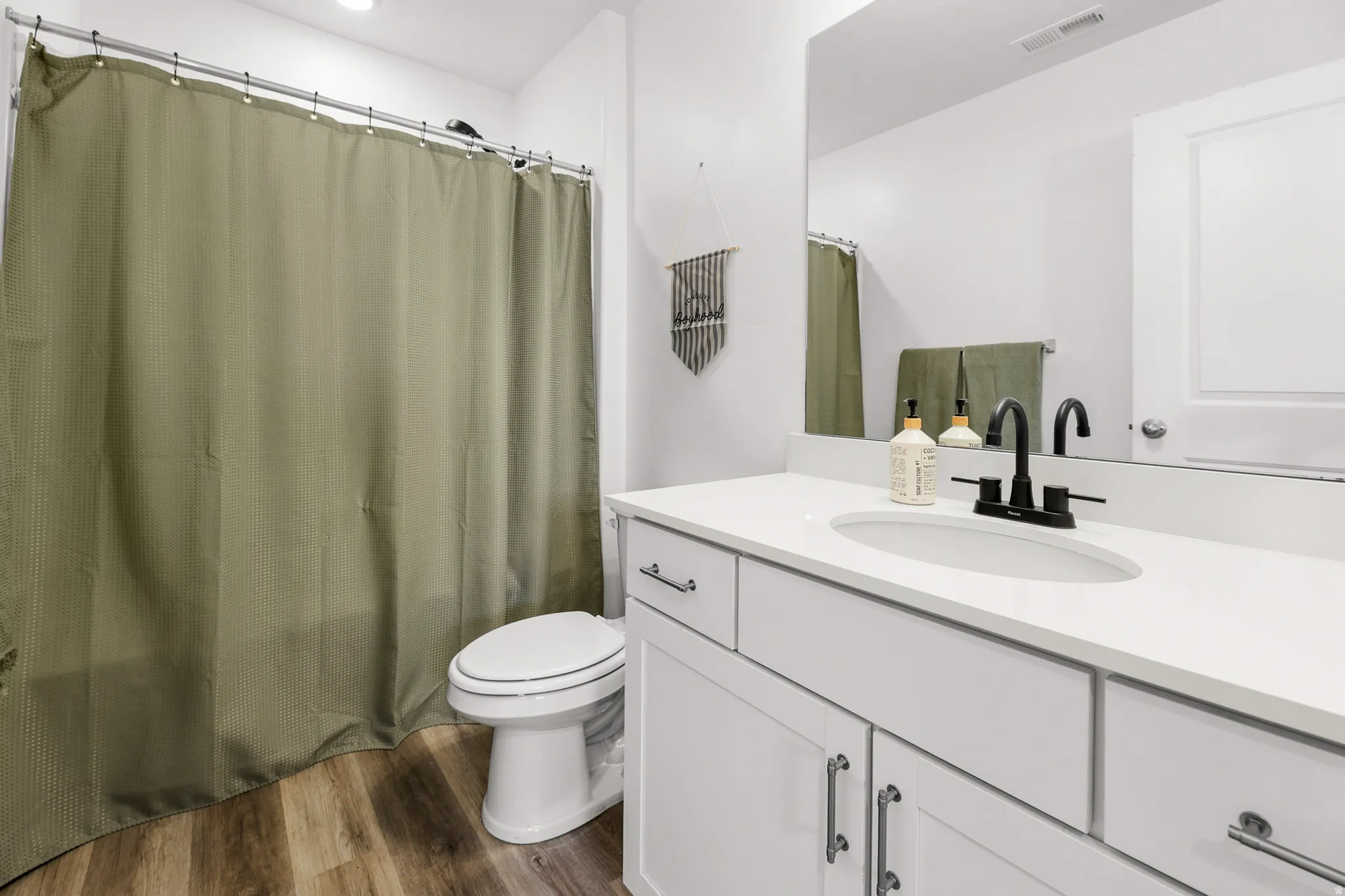 Bathroom featuring a white vanity with an integrated sink, matte black faucet, and a large mirror