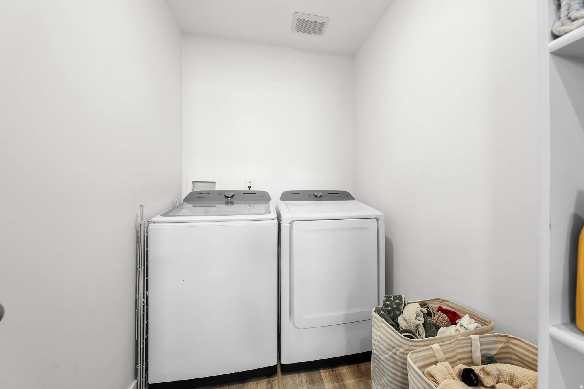 Dedicated laundry area featuring wood-finish flooring, white walls, and an overhead ventilation fan
