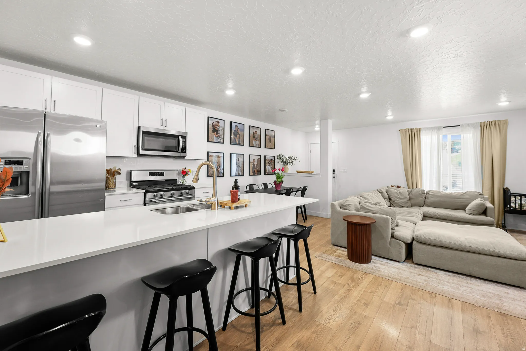 Kitchen featuring stainless steel appliances, white cabinetry, and a spacious island with seating